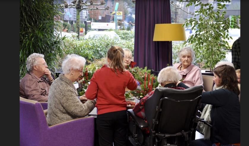 Jeugdige hulp bij het maken van kerststukjes in De Koperwiek.