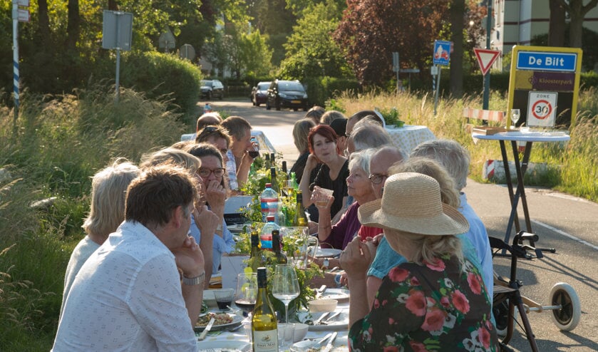 Buurtbewoners samen aan tafel in het weiland.