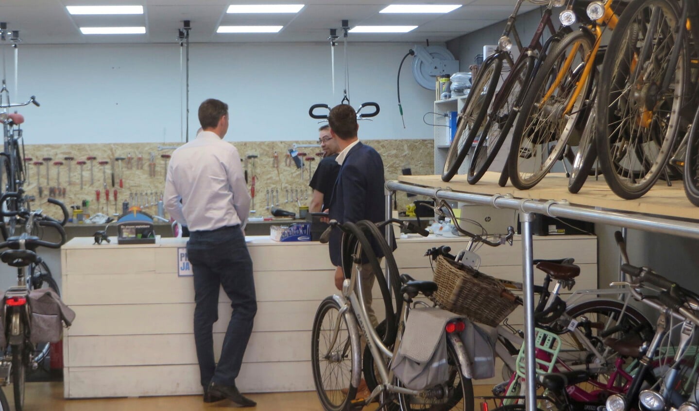 Twee Van Lodenstein-managers zoeken bij de fietsenwinkel naar informatie.