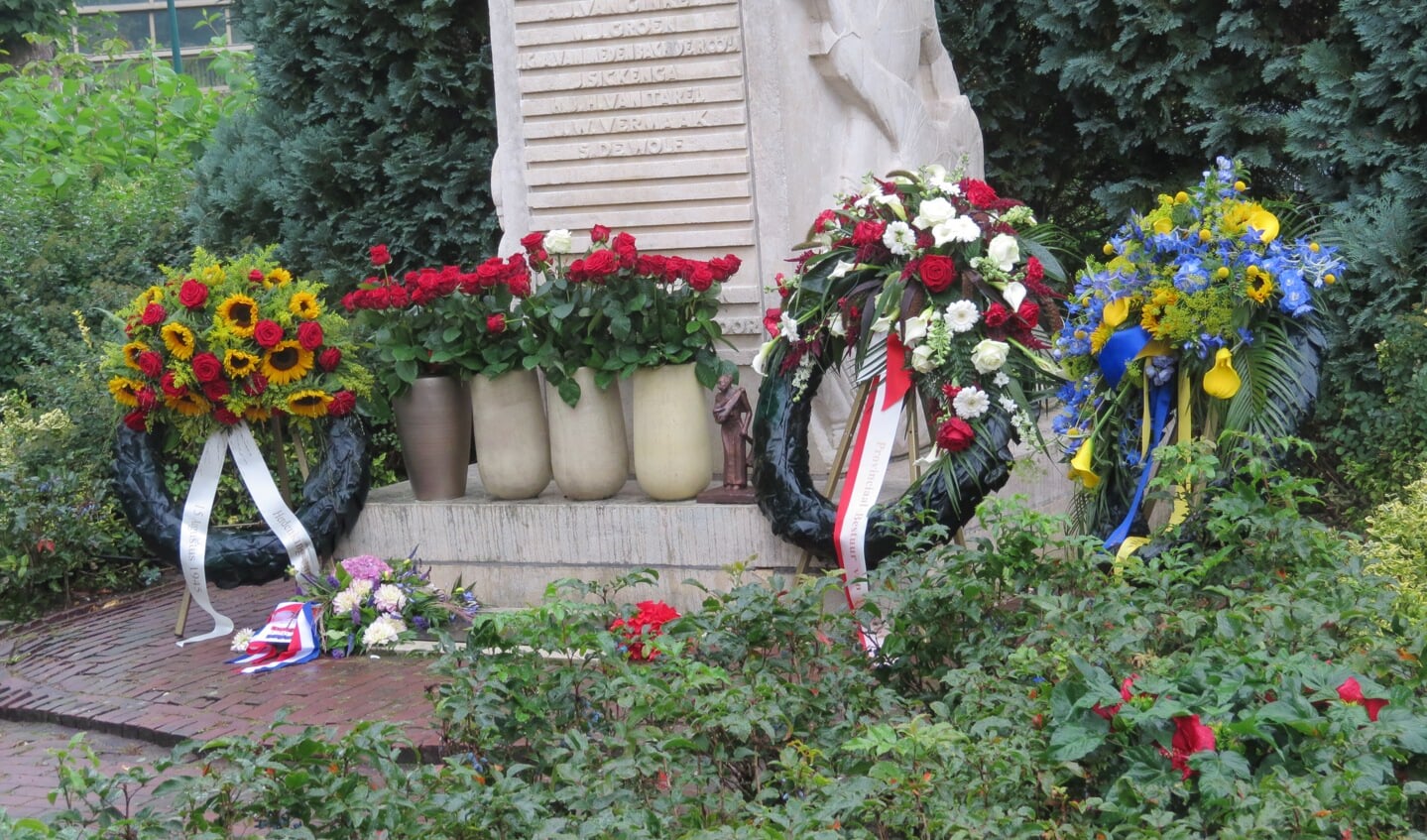 Bloemen en kransen bij het monument. 