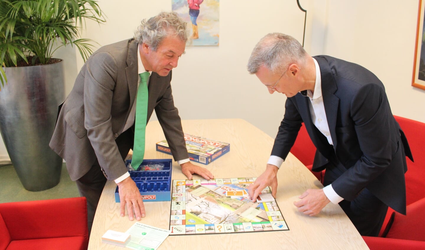 Gert Smit van PLUS heeft het monopolyspel aan wethouder Ebbe Rost van Tonningen (l) overhandigd en licht e.e.a. toe. 