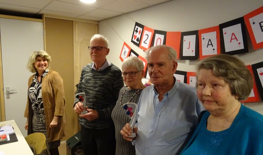 Trots tonen Gijs de Heer en Jan van Tricht de bokaal die zij zojuist uit de handen van de wethouder hebben ontvangen. V.l.n.r.: wethouder Madeleine Bakker, Gijs de Heer en echtgenote en Jan van Tricht en echtgenote.