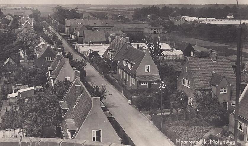 Deze foto van de Maartensdijkse Molenweg is genomen vanaf molen De Hoop en toont de in 1922 gebouwde 10 huizen voor mensen met 'huwelijksvoorrang'. Verder zijn de kassen van van der Heijden en de School met den Bijbel zichtbaar.