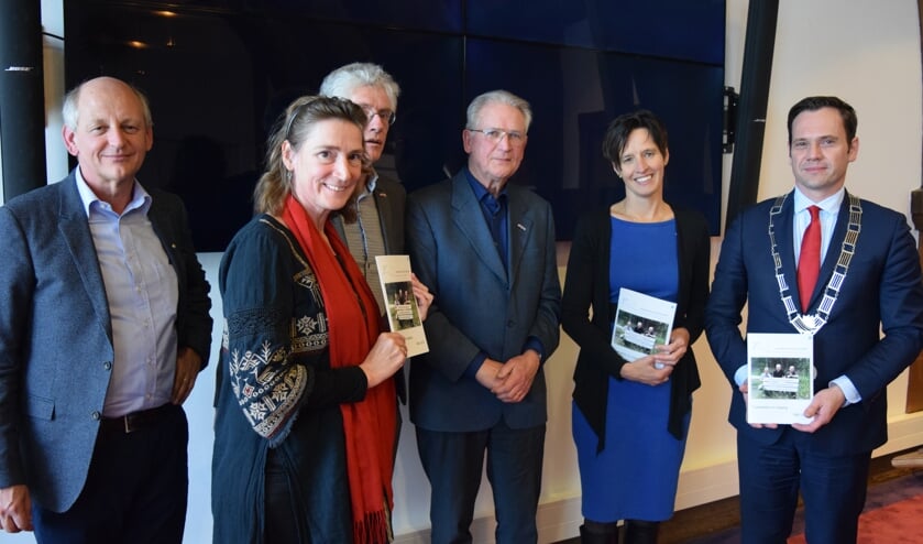 Burgemeesters Sjoerd Potters en gedeputeerde mevrouw Maasdam-Hoevers nemen het boekje in ontvangst; v.l.n.r. voorzitter Kees van Leeuwen, Henrike van Geerten, penningmeester Peter van Puijenbroek, secretaris John Bluemink, mevr. Maasdam-Hoevers en burgemeester Potters.