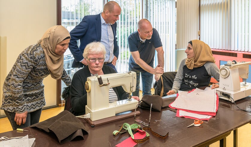 V.l.n.r. cursist Subhia Hedxishekho (krijgt uitleg over het gebruik van de naaimachine door) docent Wil Moget, Martijn van Veenendaal van Sympany en Ruud Jansen van WVT vragen cursist Walaa Awad hoe de eerste les gaat.