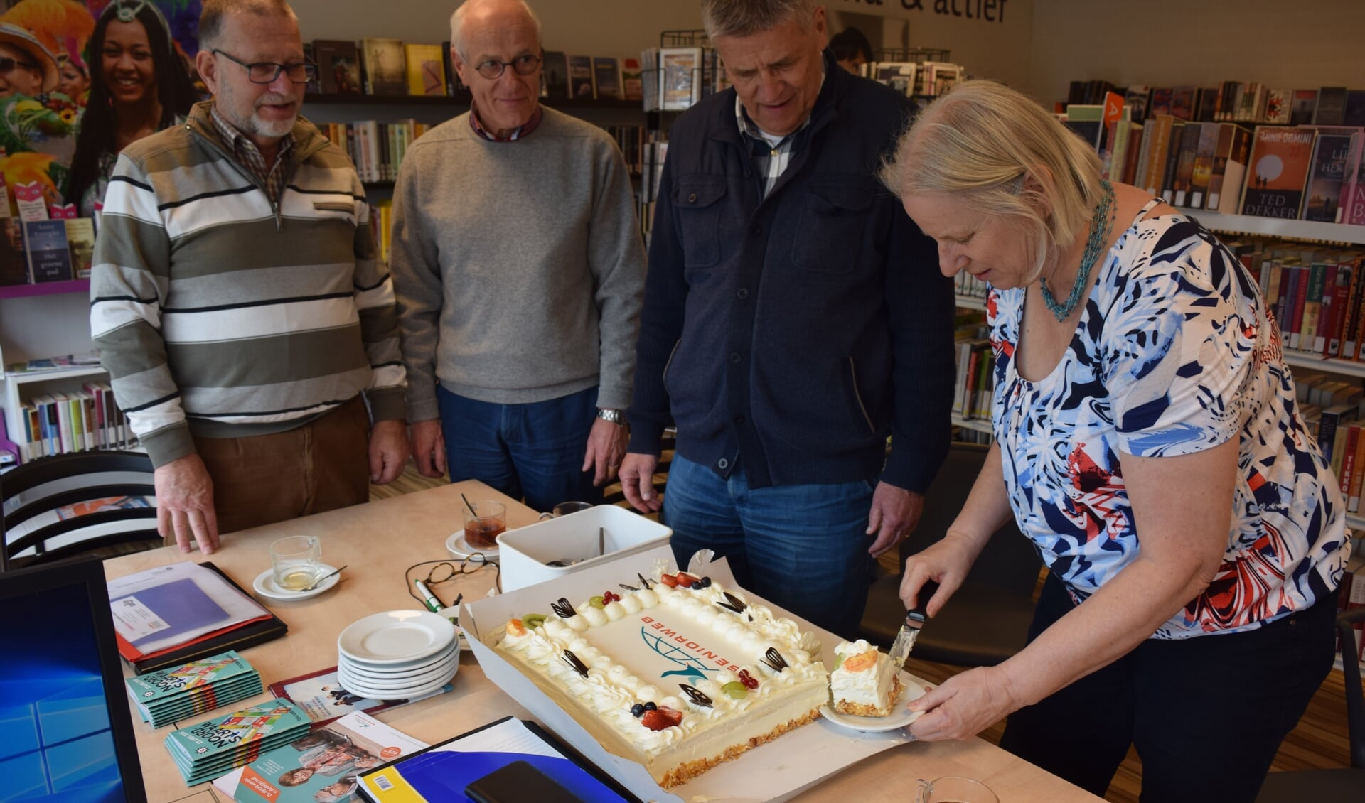 De taart wordt aangesneden door Carla Heerschop voor v.l.n.r. Ton van Doorn, Lout Bracke en Hein Banken.