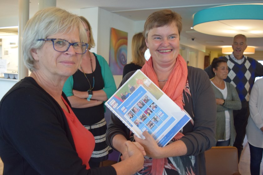 Evelien Ribbens reikt Anne Brommersma het verslag aan.