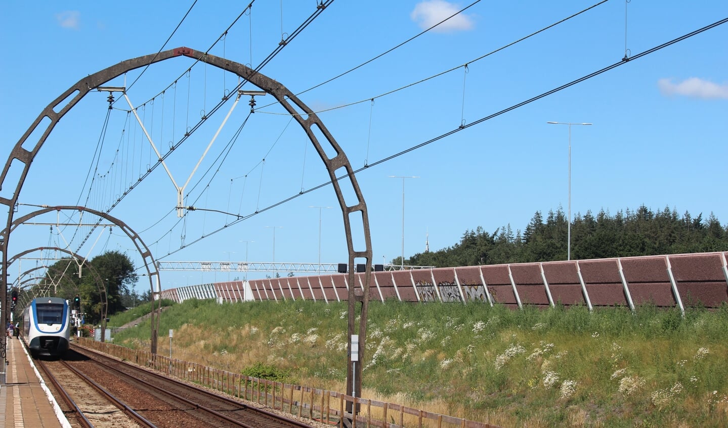 Vanaf het perron in Hollandsche Rading zijn de hoge lichtmasten (in het midden van de A27) die ruim boven het geluidsscherm, de trein en de unieke spoorbogen uitsteken, goed te zien.   