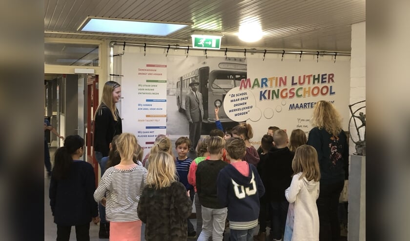 Groep 4 krijgt uitleg bij de banner in de school.