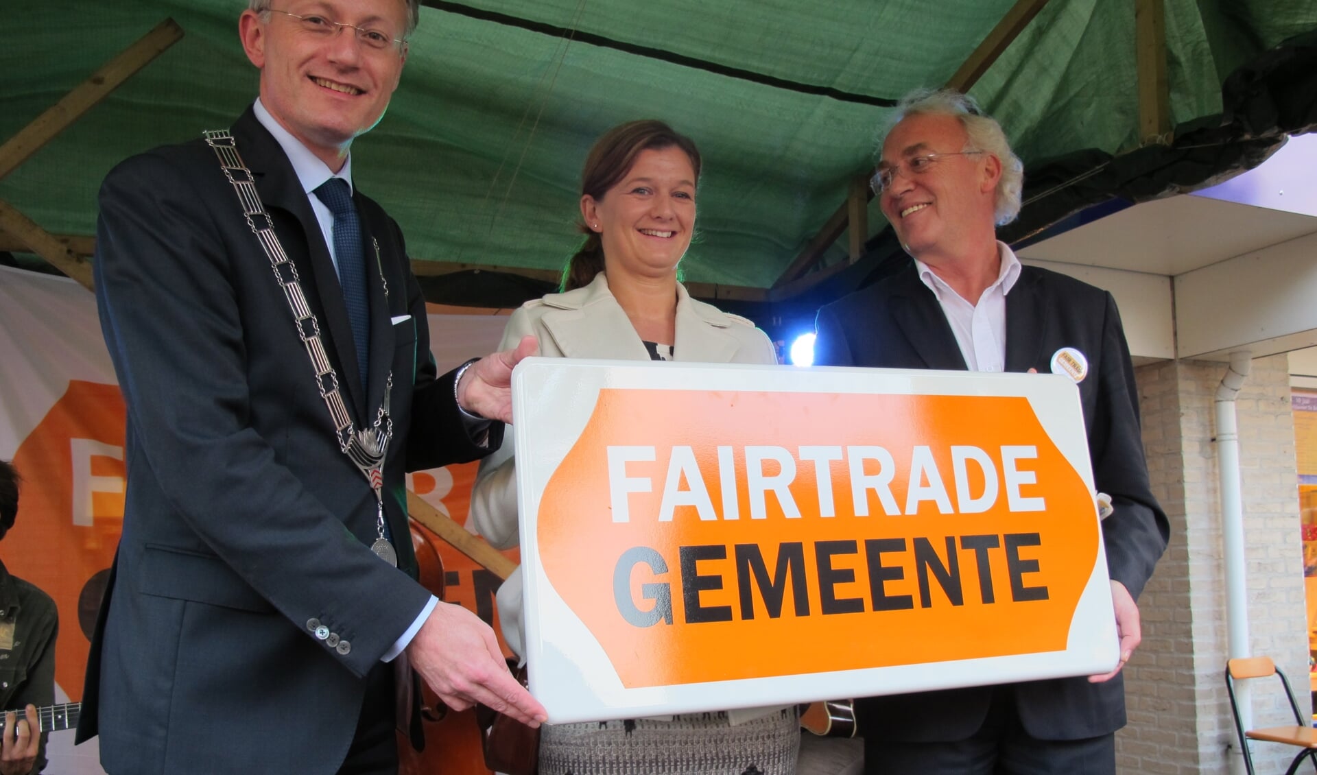 Een foto uit 2011, waarbij Liesbeth Gort (jurylid van Fairtrade Campagne Nederland) het bord Fairtrade Gemeente overhandigd aan voormalig burgemeester Arjen Gerritsen en voormalig wethouder Herman Mittendorff. [foto Lilian van Dijk]