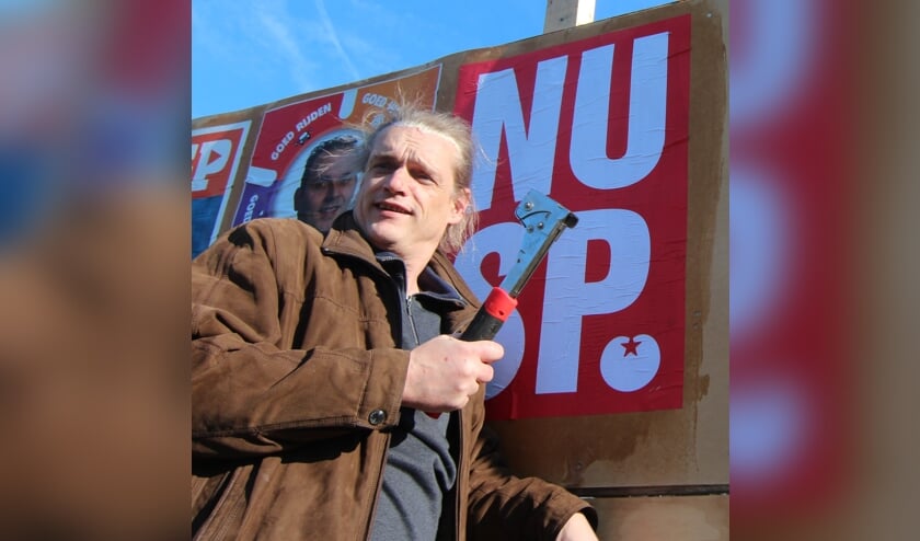 Gemeenteraadslid Menno Boer plakt en niet op een van de verkiezingsborden in de gemeente.