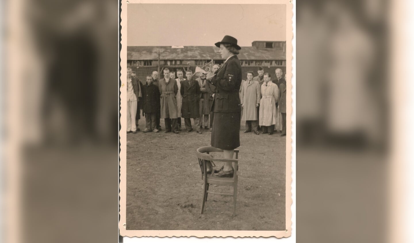 Loes Overeem spreekt direct na de oorlog staande op een stoel in Kamp Amersfoort de kampbewoners toe. (fotograaf onbekend/ Kamp Amersfoort)