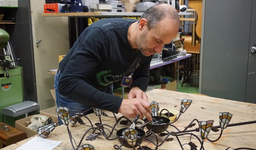 Reparateur Roger onderzoekt wat er mis is met de sierlamp van een bezoeker uit De Bilt.