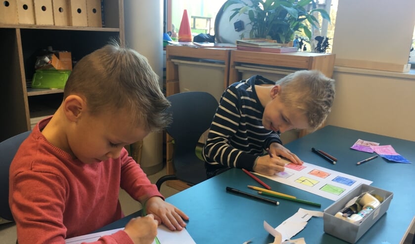 Twee leerlingen uit groep 3 zijn in opperste concentratie aan het werk om een mooi rekenspel te maken voor de kinderen in Abong Mbang.