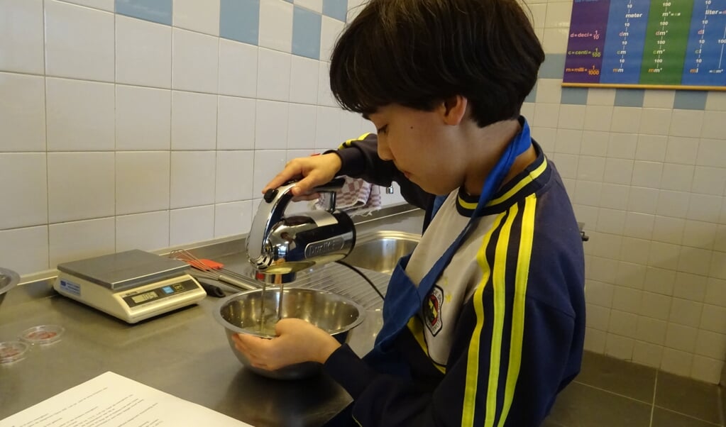 Een leerling bezig in het kooklokaal met het bereiden van ijs.
