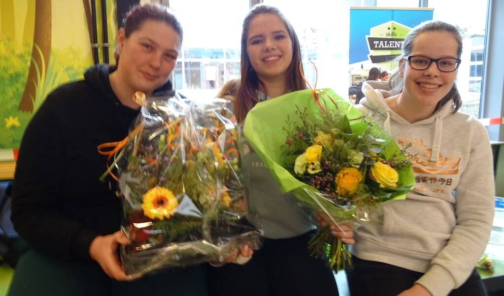 Fenna, Tess en Simone tonen trots het door hen gemaakte bloemwerk. 