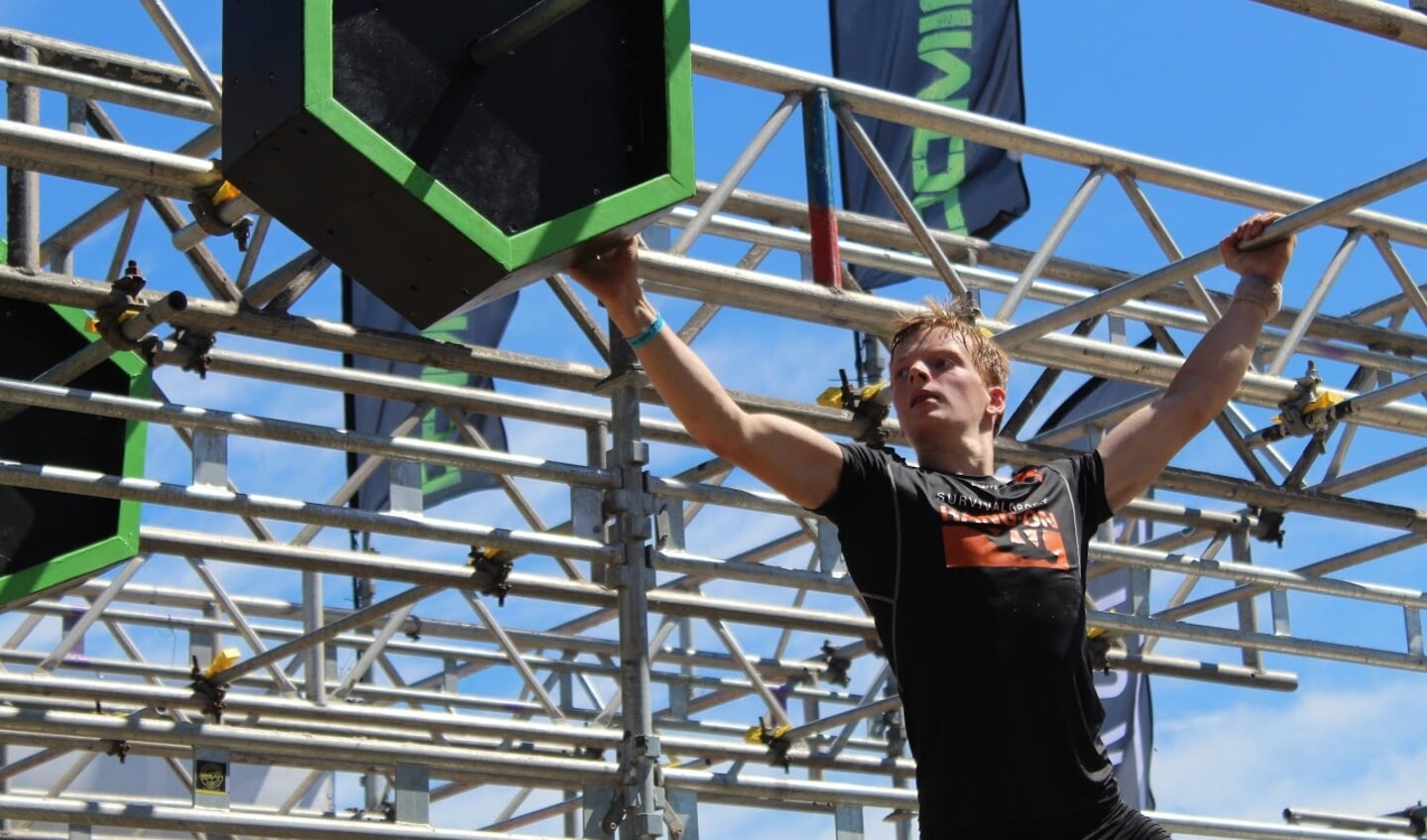 Stijn in actie op hindernis Monkeybars waarbij het op kracht in de armen, techniek en gripkracht in de handen aankomt.