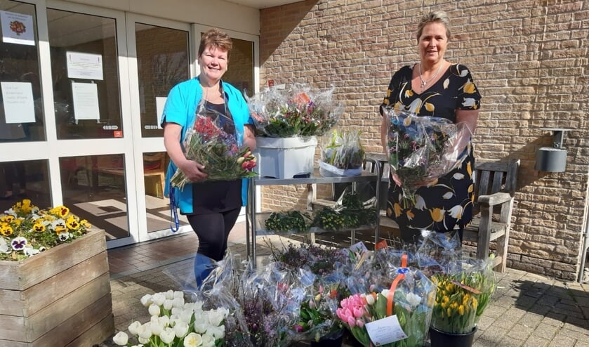 Nicolien Ahaidour en Lia Bicker, zorgmedewerkers van de Bremhorst, nemen 50 bossen bloemen in ontvangst.