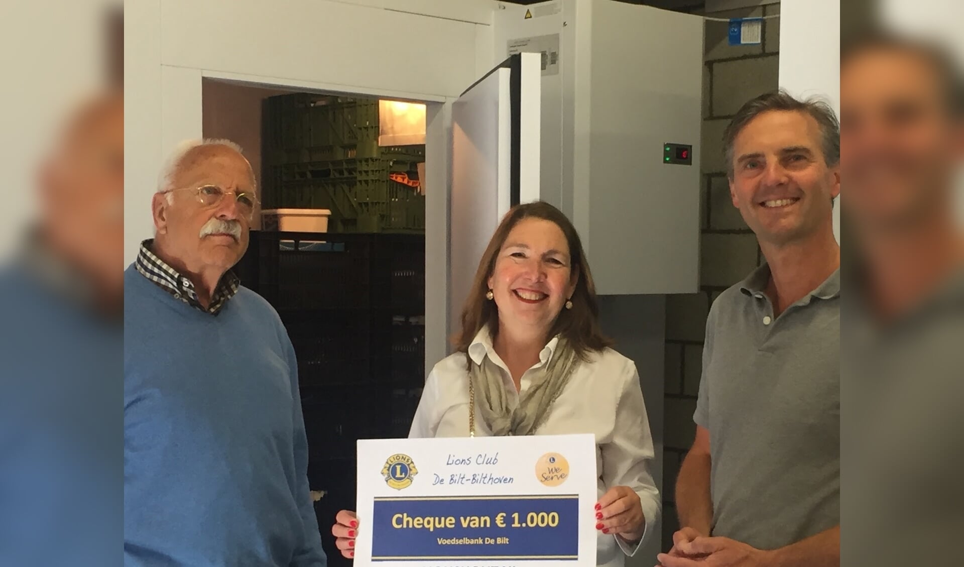 Voorzitter van de Voedselbank, Jolanda van Hulst, staat met de heren Lindenbergh (l) en van Driel (r) van de Lionsclub De Bilt Bilthoven voor de koelinstallatie. 