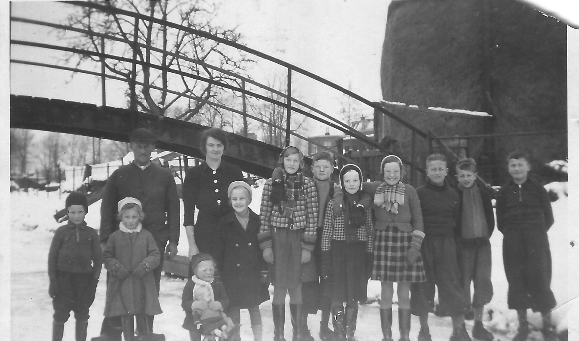 Eef(je) zittend op de slee met haar zus (links), vader en moeder en overige buurtkinderen op het ijs van De Grift bij de een aantal jaren geleden afgebroken brug ter hoogte van de benzinestations.