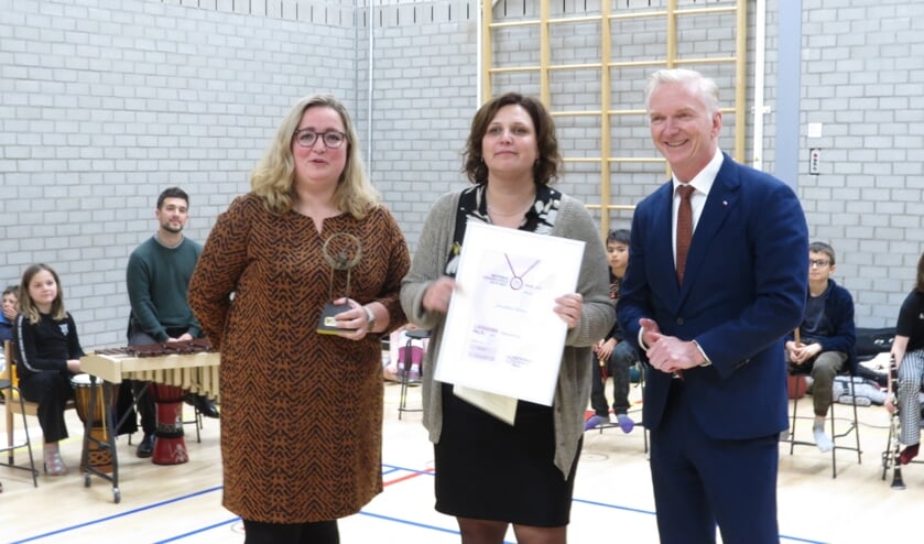 Nadine ten Kate en Linda Kuijt nemen trots de prijs in ontvangst van gedeputeerde Robert Strijk.