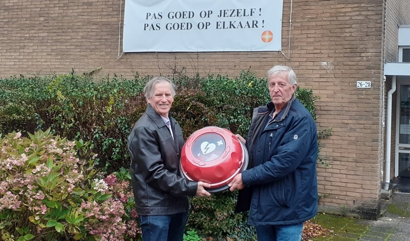 Voorzitter Ed Schaefers (links) overhandigt de AED Buitenkast aan Argo Burger (vertegenwoordiger van de Ontmoetingskerk in Maartensdijk).