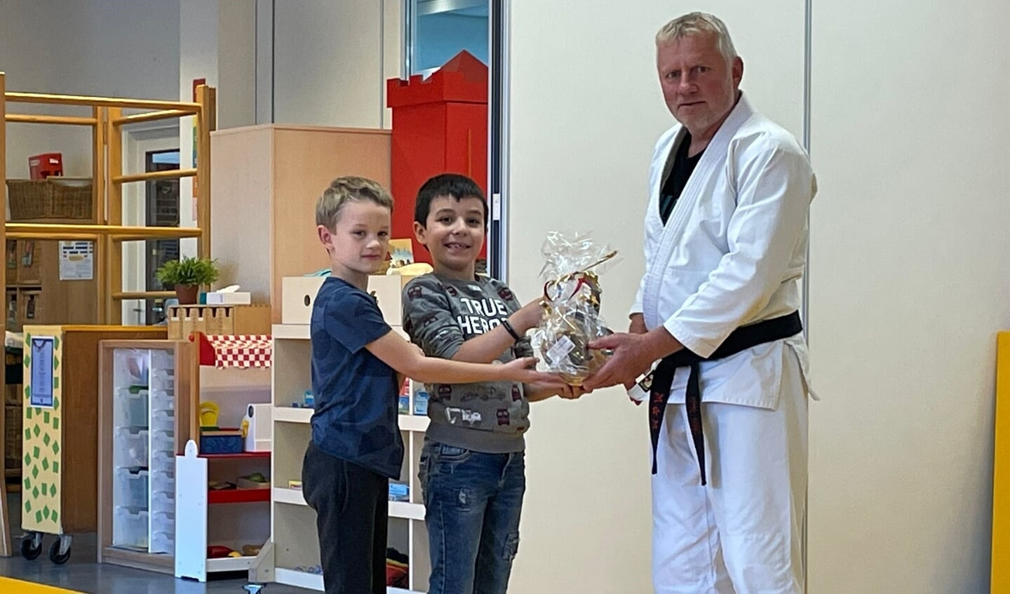Judoleraar Martin Koudijs deelt lekkers uit aan de kinderen voor hun positieve inzet tijdens de judolessen.