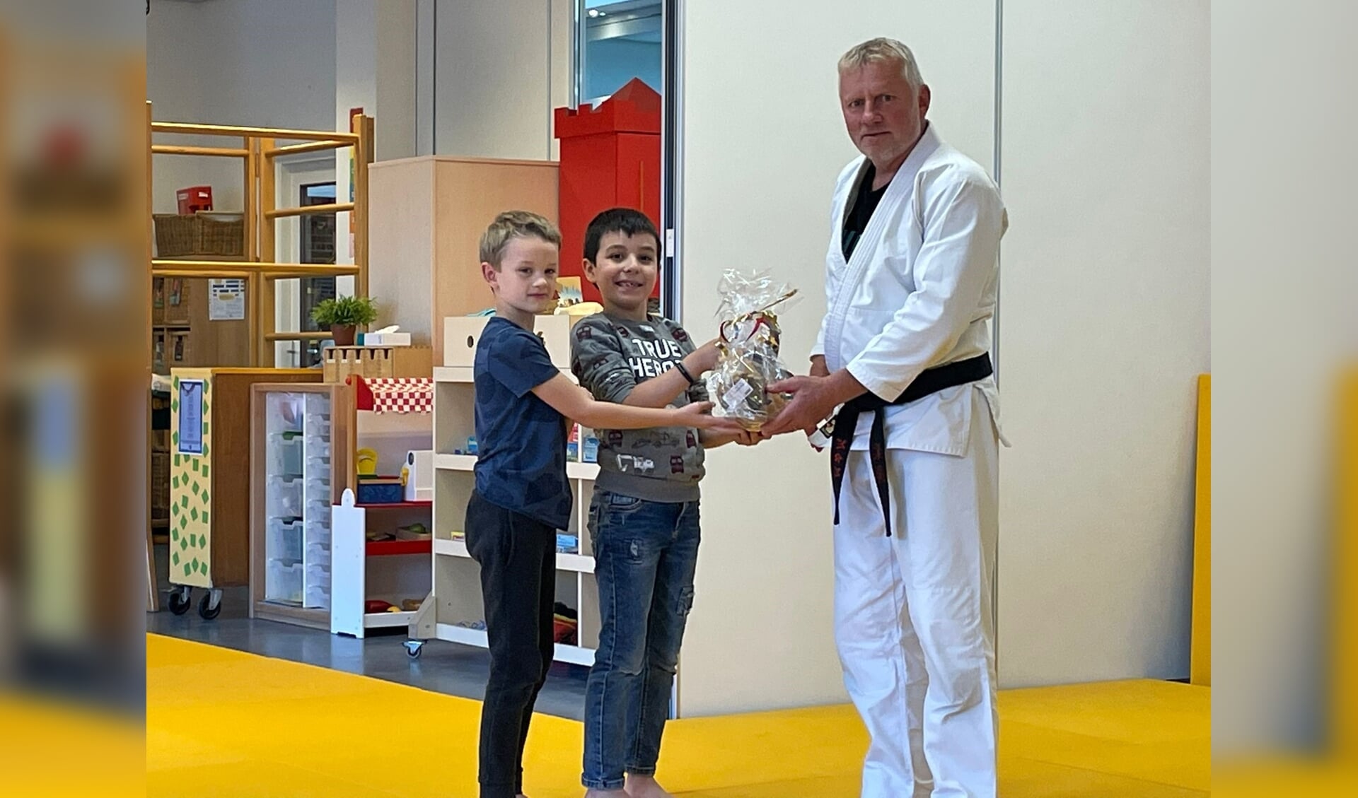 Judoleraar Martin Koudijs deelt lekkers uit aan de kinderen voor hun positieve inzet tijdens de judolessen.