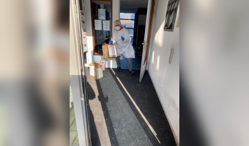 Een medewerker van De Reiger (Reinaerde) pakt namens de Kroegbezoekers de tasjes aan. Vanwege besmettingen en quarantaine is voorzichtigheid geboden, maar een carnaval vieren gaan ze wel doen.