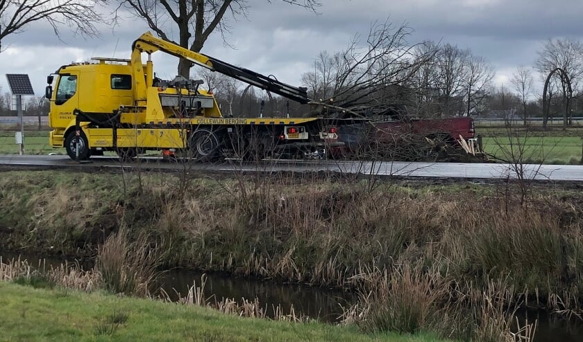De brandweer heeft de boom die over de auto lag, afgezaagd waarna de berger de auto kon afvoeren. (foto Marcel Röhrs)