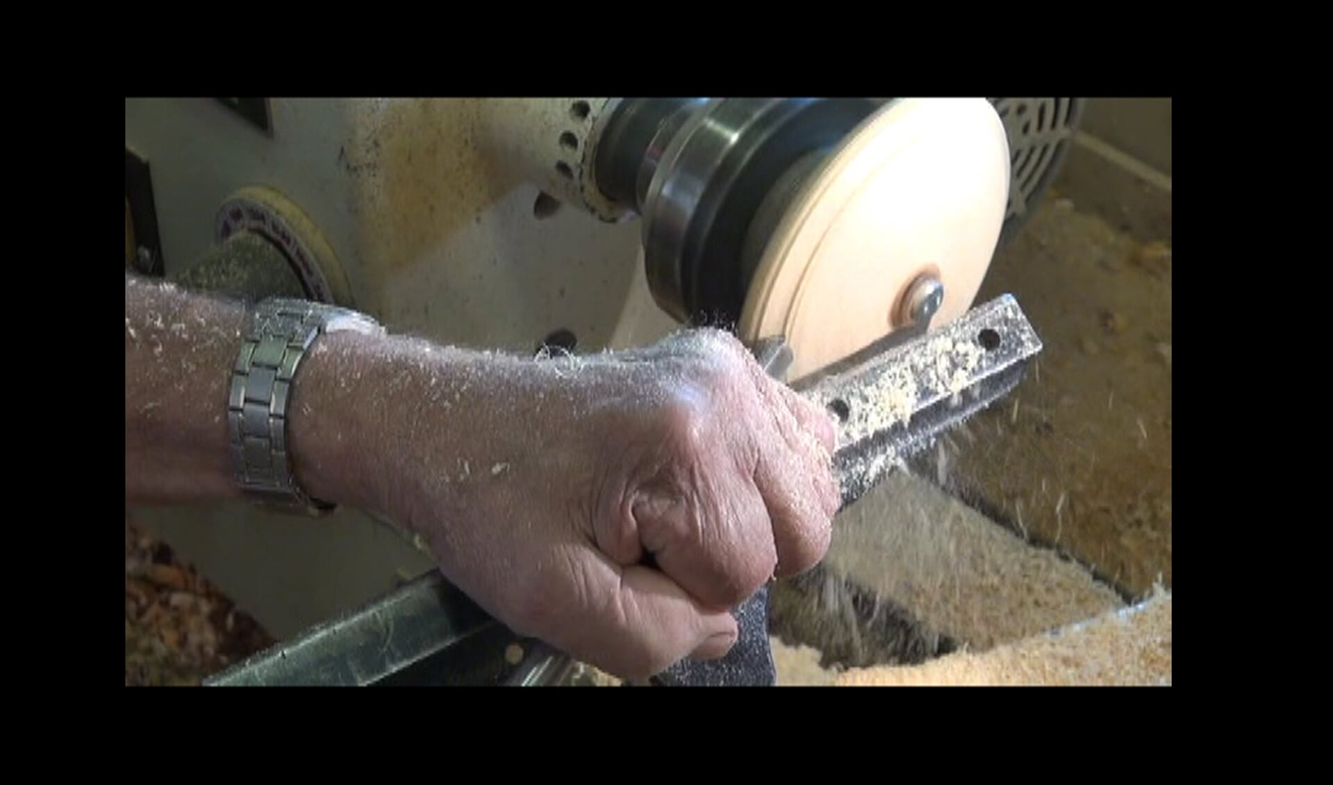 Vaardige handen bedienen de moderne draaibank. Vormen het ruwe stuk hout tot een fraai product.