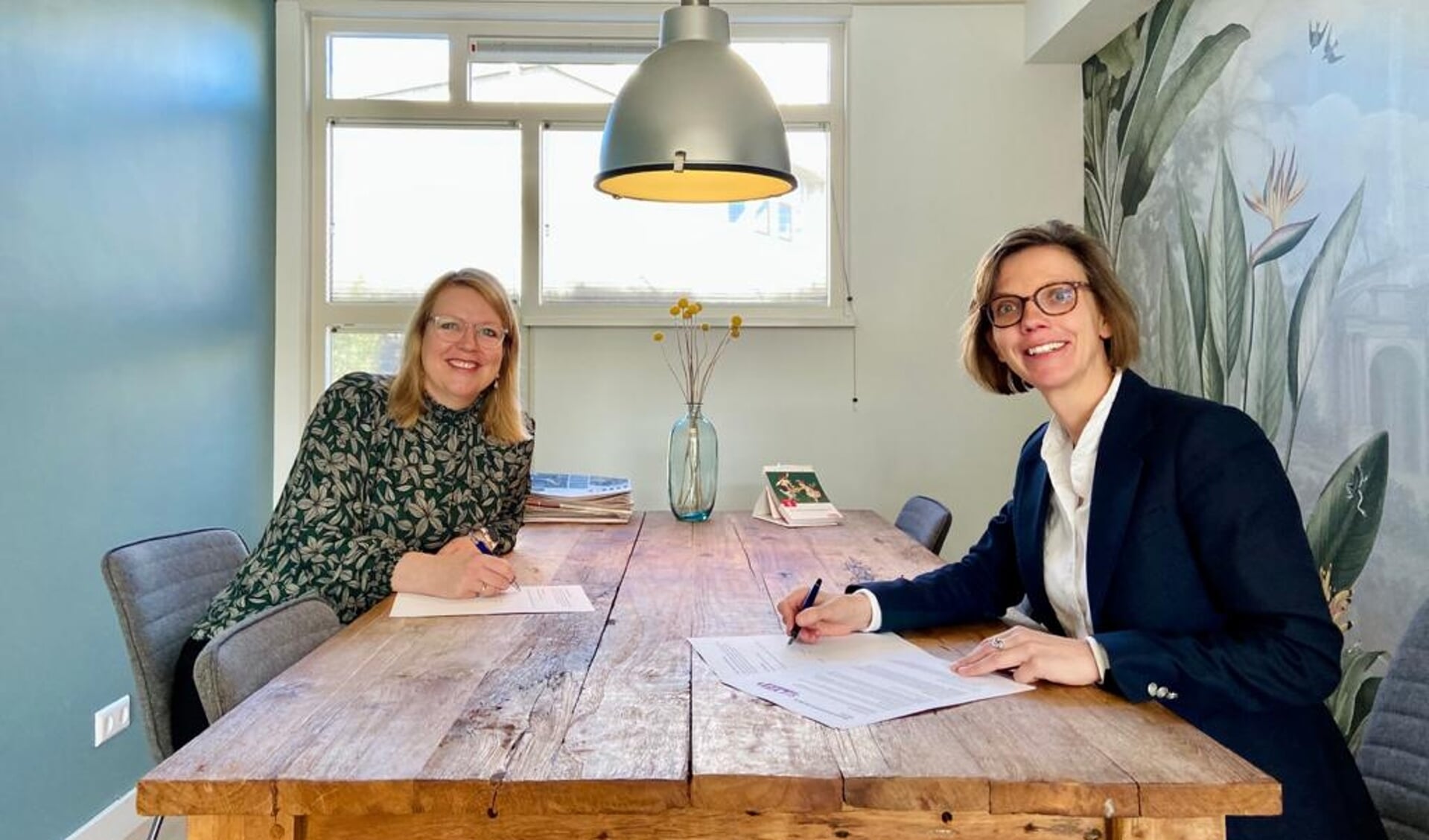 Fleur Imming (links) en Saskia Knoop (rechts) tekenen het sponsorcontract