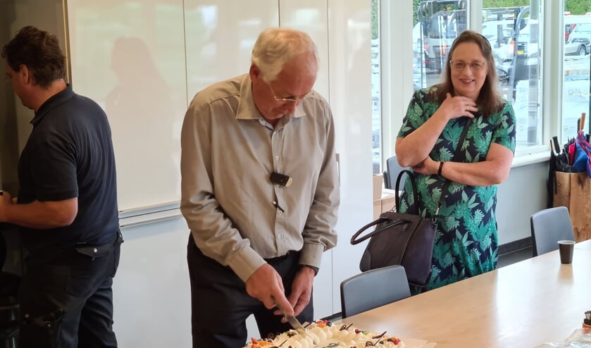Onder toeziend oog van Ria snijdt Wijnand Hennipman op zijn jubileumdag zelf de taart aan.