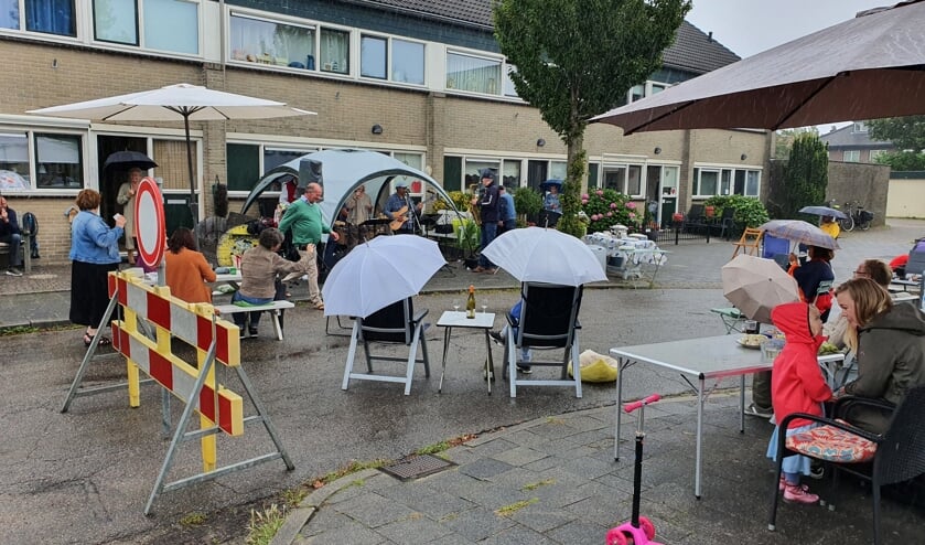Ondanks de vele regen kwamen omwonenden met eten, drinken en paraplu's om te luisteren naar nummers van de A.S. Streetband.