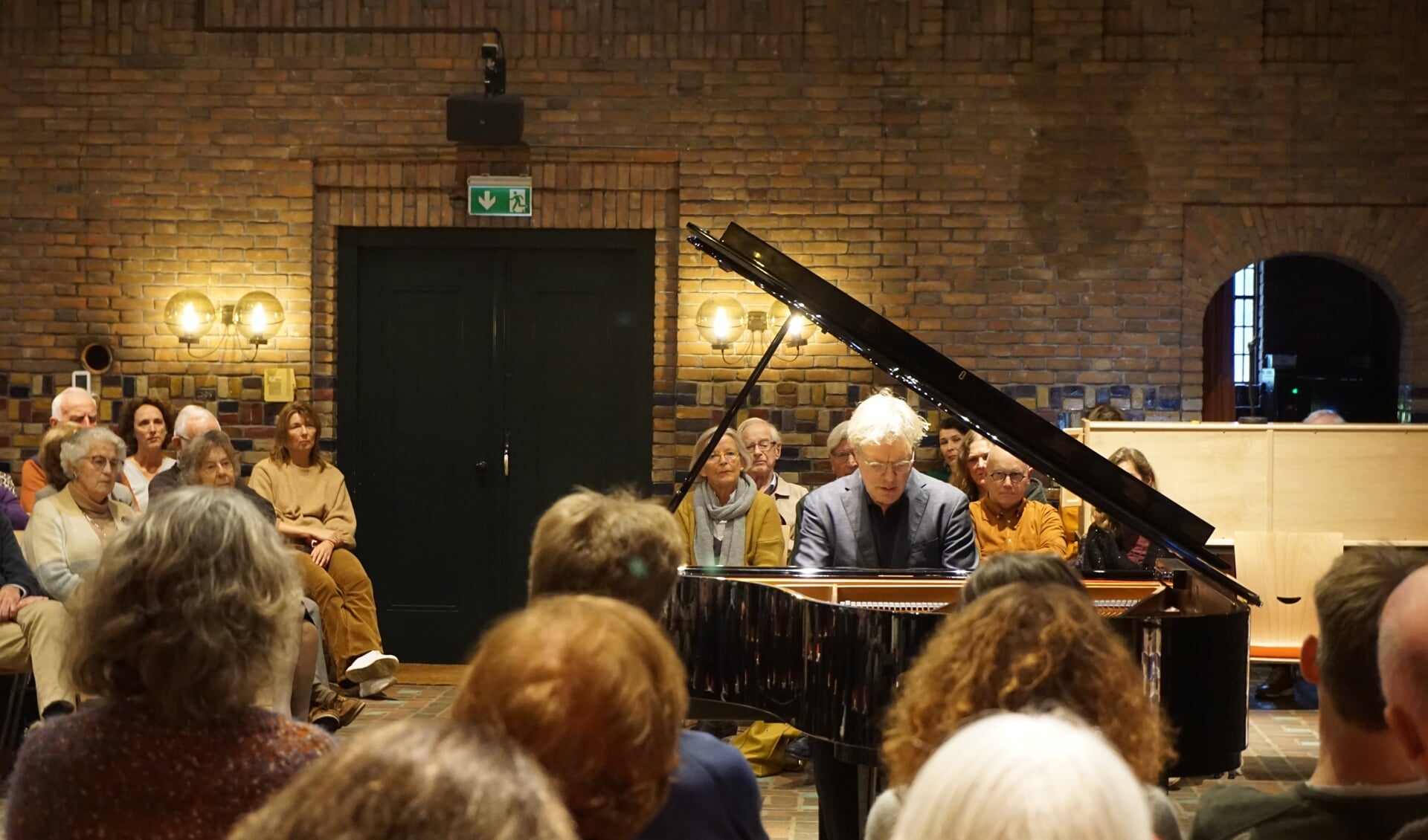 Kees Wieringa, in een volle zaal van de Woudkapel tijdens een muzikaal intermezzo op de vleugel.