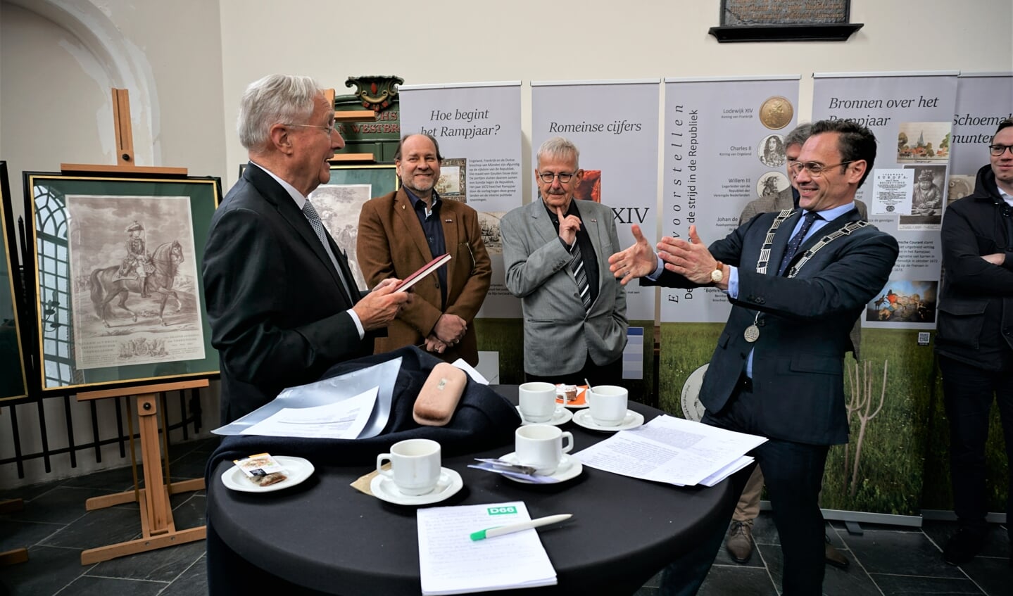 Burgemeester Sjoerd Potters krijgt een aantal boekjes overhandigd.