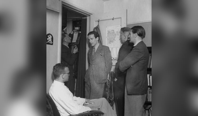 Medewerkers van Berg en Bosch luisteren aandachtig naar een illegale radio uitzending op een verboden radiotoestel. Radio's werden in mei-juni 1943 door de Duitsers gevorderd.  