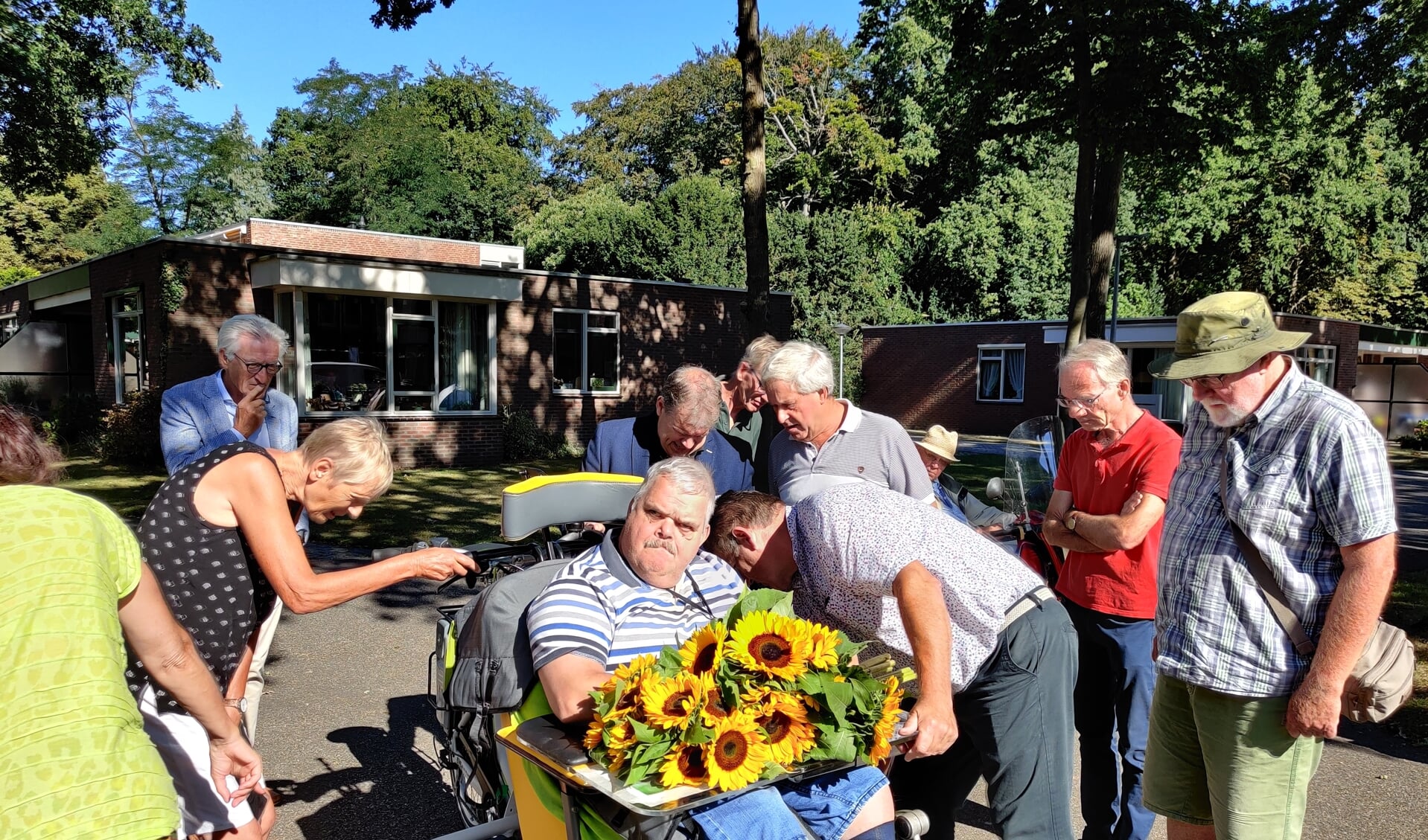 Bewoners van d’Amandelboom bekijken vol bewondering de nieuwe rolstoelfiets.