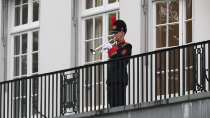 Guus van Wijk staat op het balkon van Jagtlust klaar om het taptoesignaal te blazen.