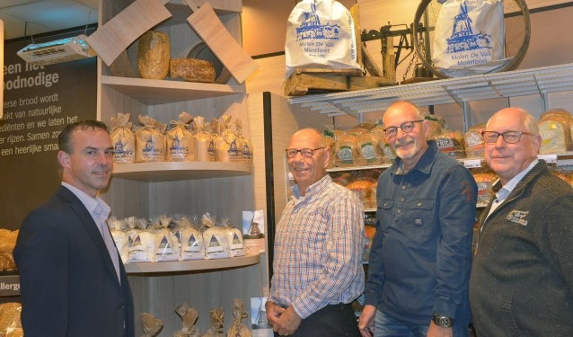 Wilco Versluis van de Albert Heijn, Hans van Domselaar, molenaar Henk Visser en Kees Birkhoff van molen De Valk bij de uitgestalde producten.