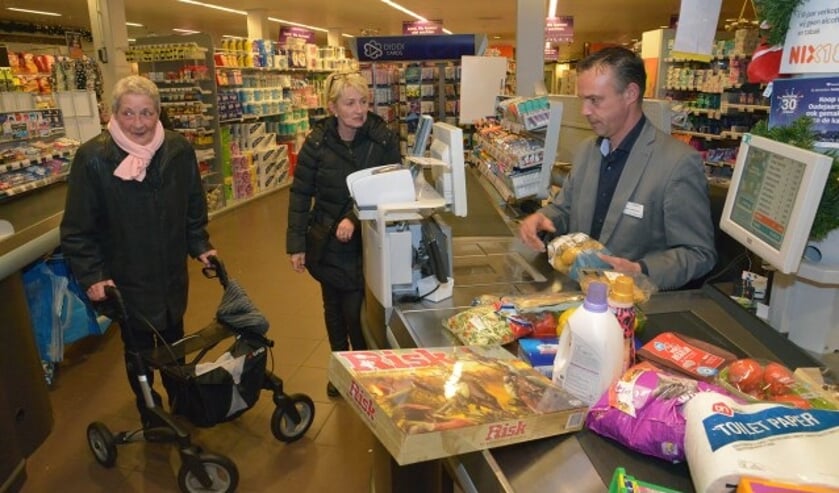 Winnares Rina van den Haselkamp met dochter Anita kijken toe hoe Wilco Versluis van AH Montfoort de boodschappen scant. (Foto en tekst: Paul van den Dungen)