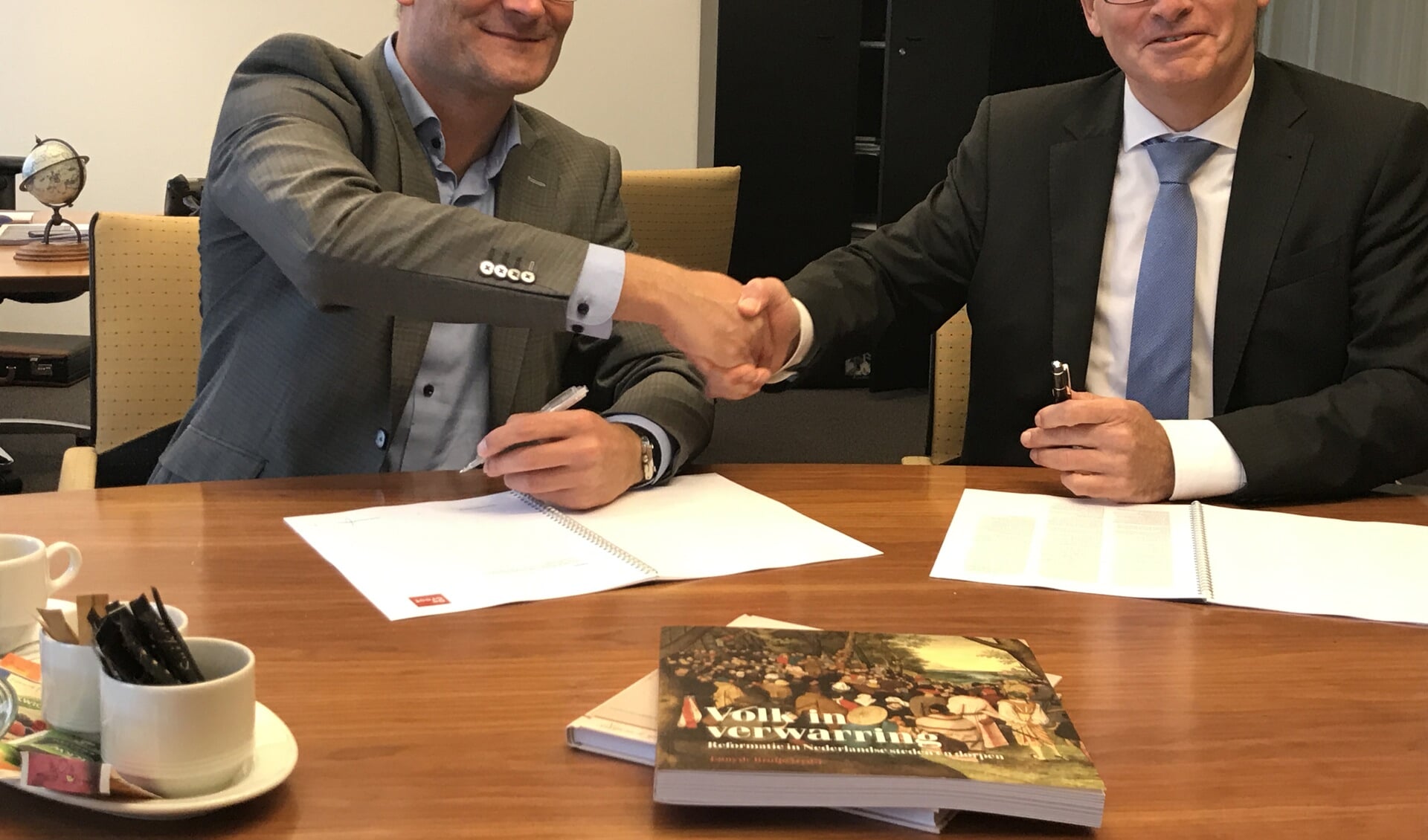 • Wim Everts (links) en Bart Visser schudden elkaar de hand na de ondertekening.