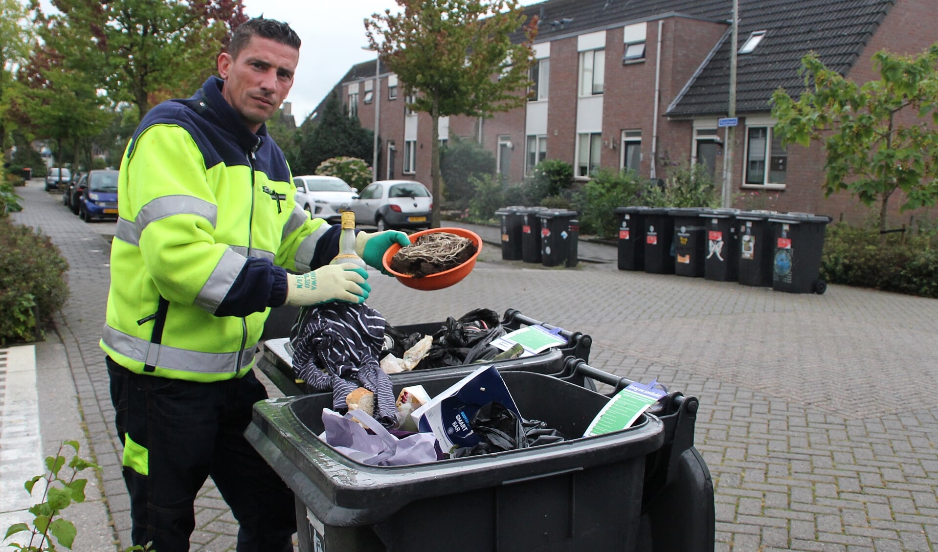 • Jan van der Grijn toont 'verkeerd' afval in enkele PMD-containers in Groot-Ammers. Foto: Bert Bons
