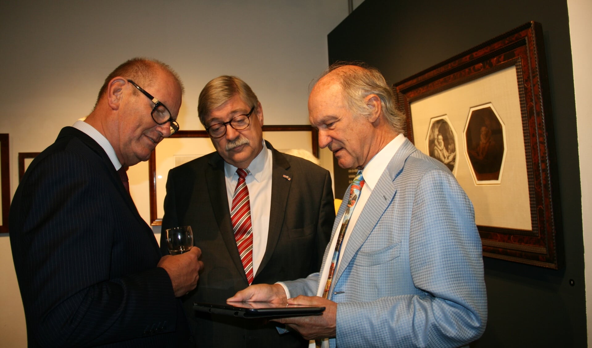 • Collectioneur Jaap Mulders (r.) geeft met behulp van een tablet aan burgemeester Groeneweg (l.) en cdk Van Beek (m.) toelichting op één van de tentoongestelde etsen van Rembrandt. 