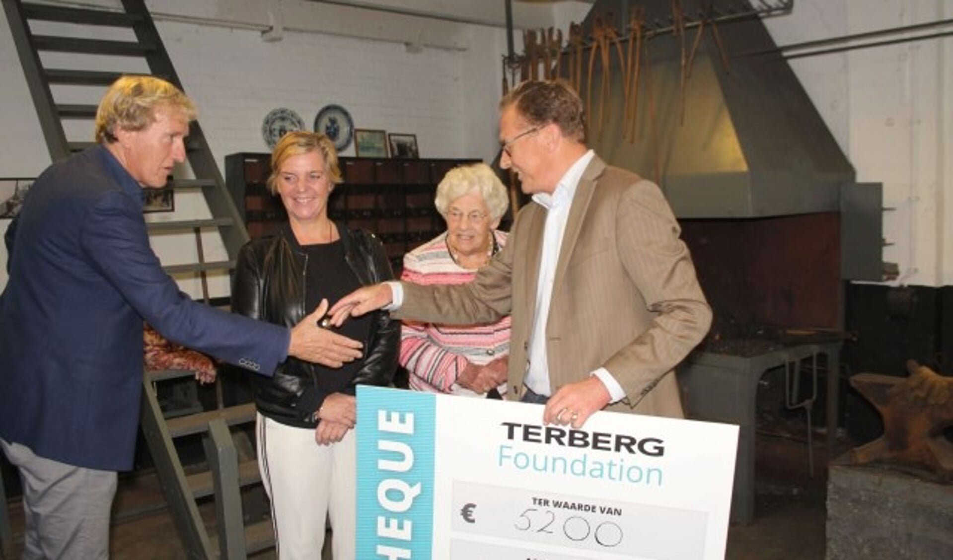 Jan Terberg overhandigt met nicht Marlies en tante Nel de cheque in de Smederij aan stichting De Warmtebron. (Foto: Lysette Verwegen)