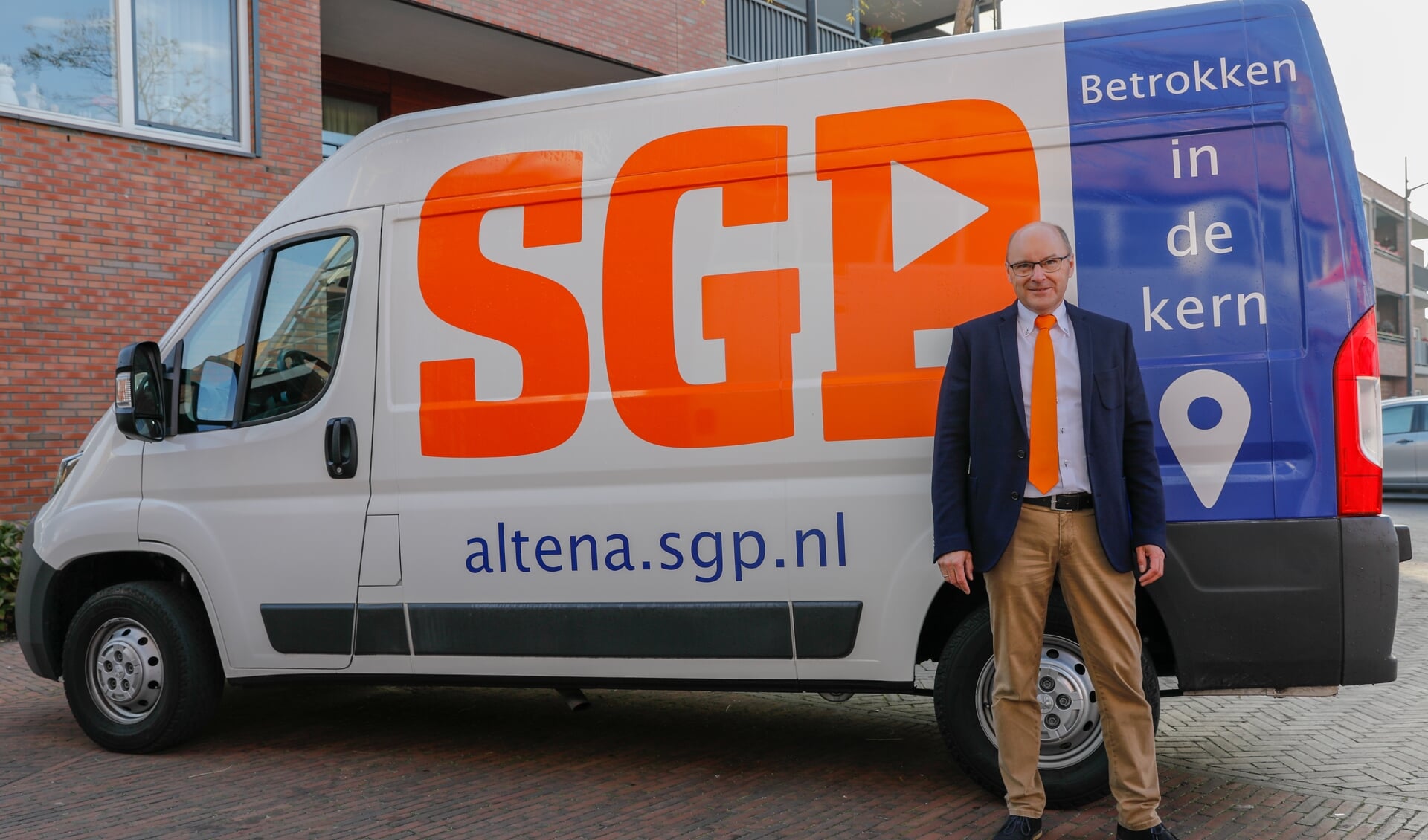 Jan Bossenbroek bij de SGP-bus die de deze weken veelvuldig in Altena te zien is.