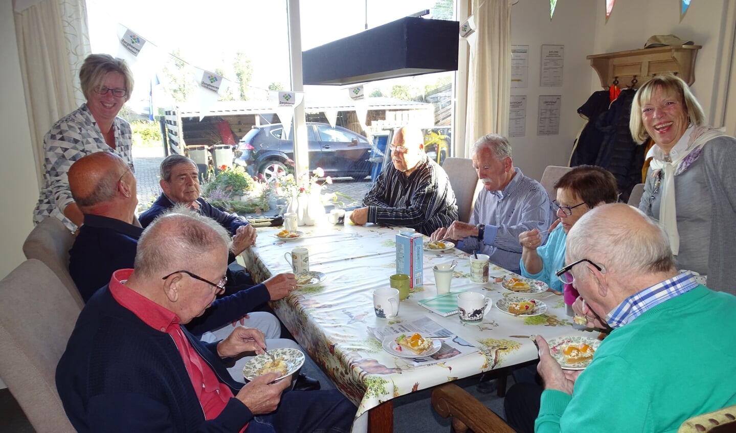 • Begeleiders Anja, Henk en vrijwilligster Jeanette genieten samen met de ouderen van een feestelijke traktatie.
