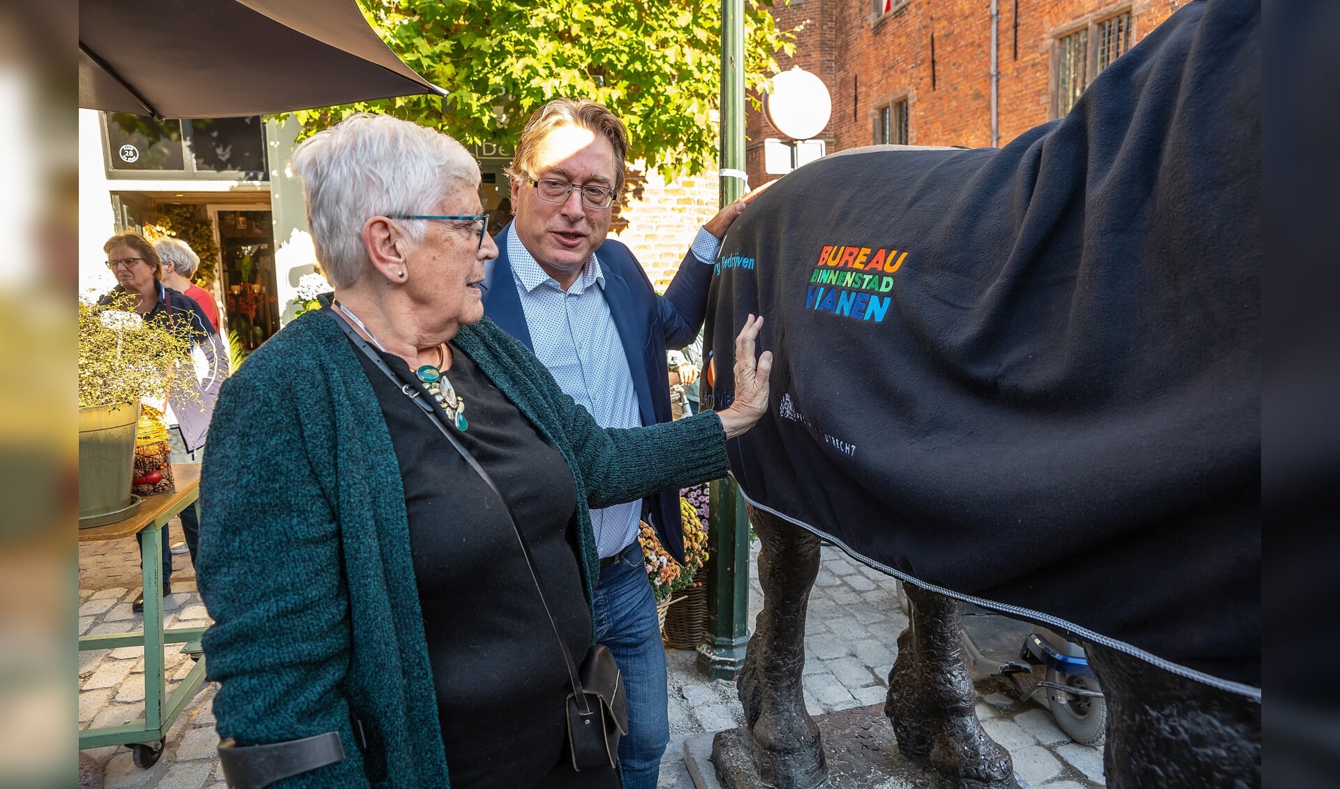 • Wethouder Frank Meurs en oud-wethouder Thea Schaafsma leggen een deken op het bronzen beeld 'Het Paard', dat deze week weer teruggeplaatst is na de afronding van de bestratingswerkzaamheden aan de Voorstraat. 