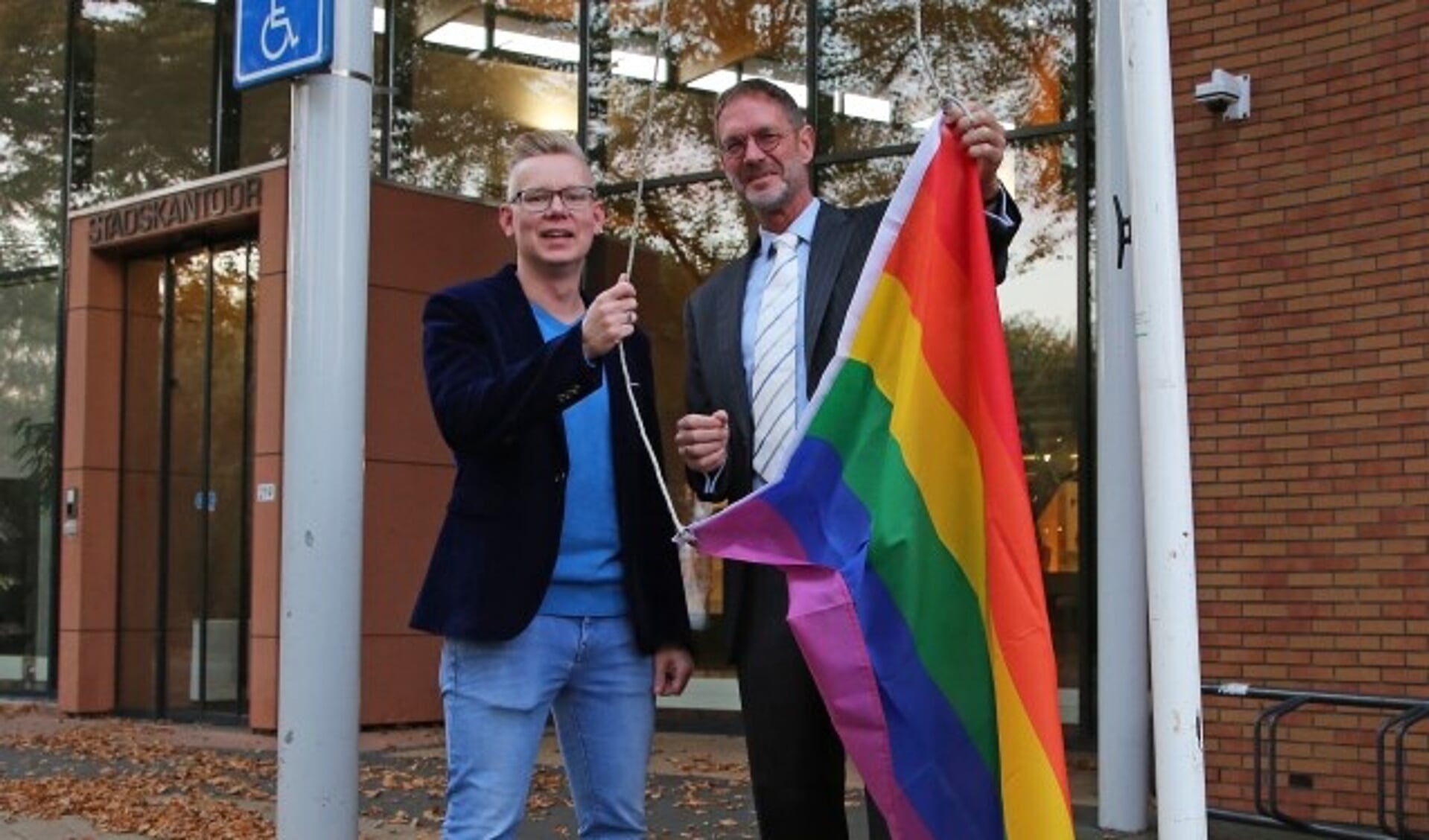 Wethouder Bob Duindam van Oudewater en Remon van Breukelen hijsen de regenboogvlag.