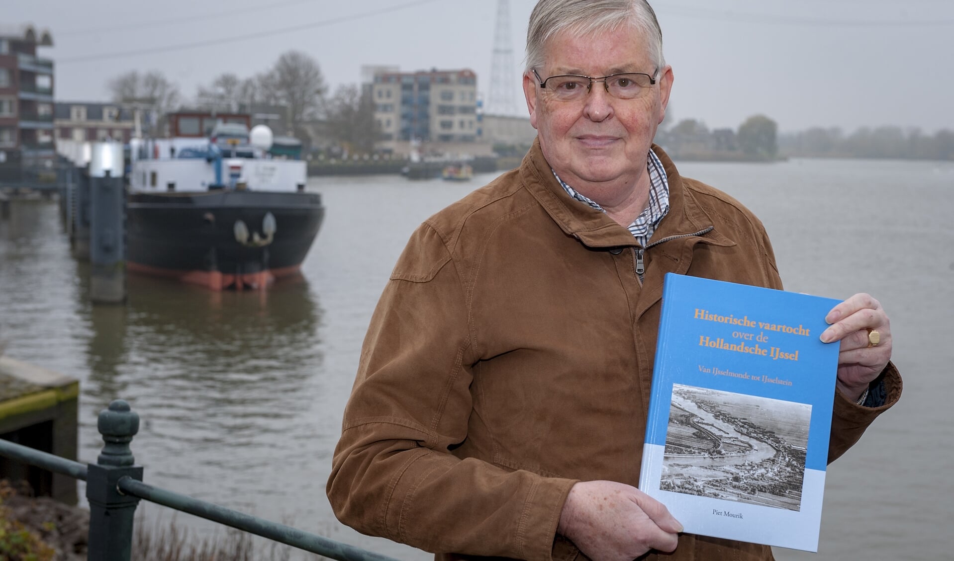 • Piet Mourik met op de achtergrond het havenfront van Ouderkerk aan den IJssel.  